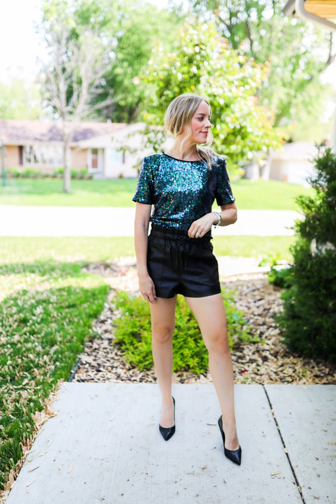 woman wearing faux leather shorts, sequin top and black heels