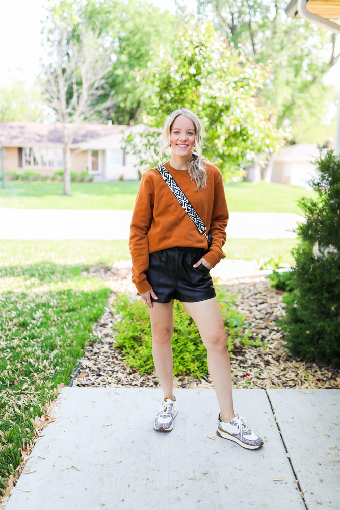 woman wearing faux leather shorts and orange sweatshirt