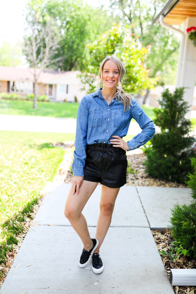 woman wearing faux leather shorts with chambray top and black sneakers