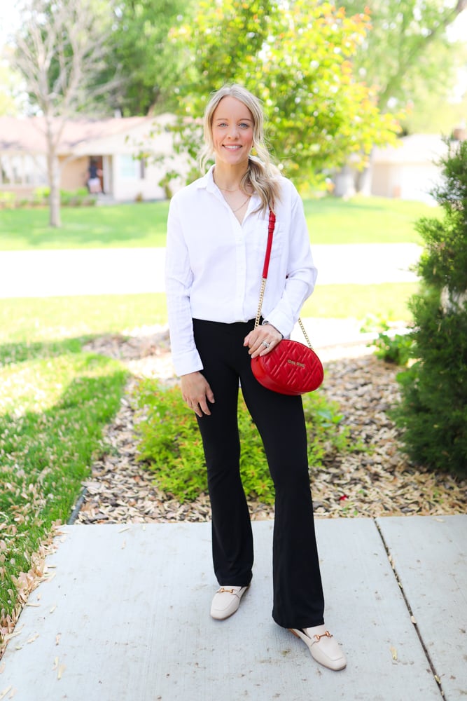 Woman wearing flare leggings with white button down, mules and crossbody bag.