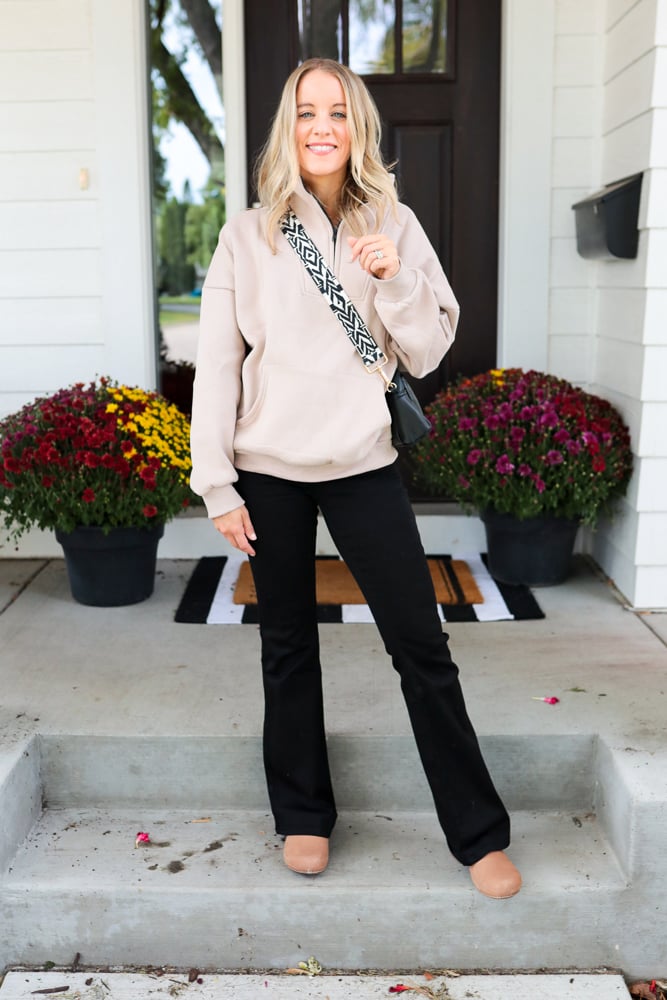 woman wearing black flare jeans, sweatshirt and clogs