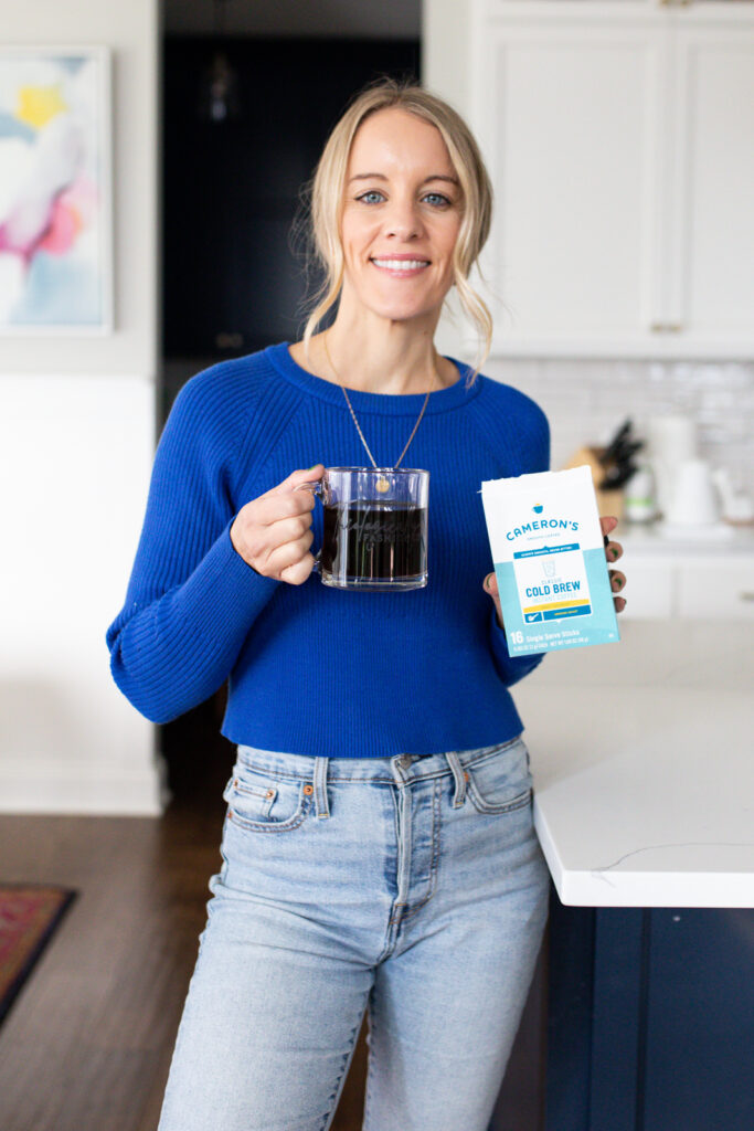 woman holding cup of coffee and cameron's coffee box of instant coffee