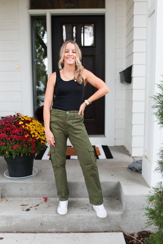 woman wearing green cargo pants, black tank top and white sneakers