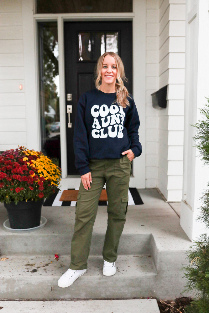 woman wearing green cargo pants, cool aunt club sweatshirt and white sneakers