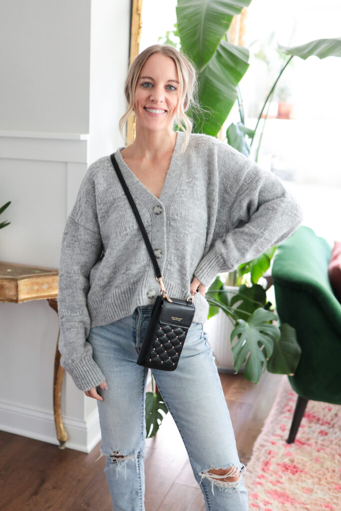 woman wearing a grey cardigan jeans and black crossbody bag
