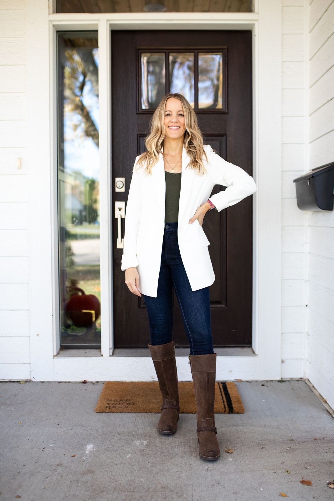 woman wearing a white blazer and jeans with riding boots