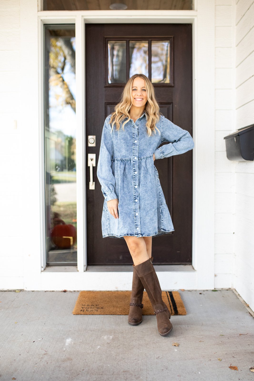 A woman wearing a blue chambray dress with brown riding boots