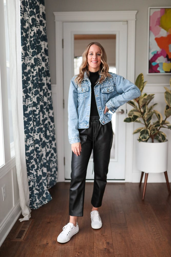 Woman wearing black turtleneck, denim jacket and faux leather joggers