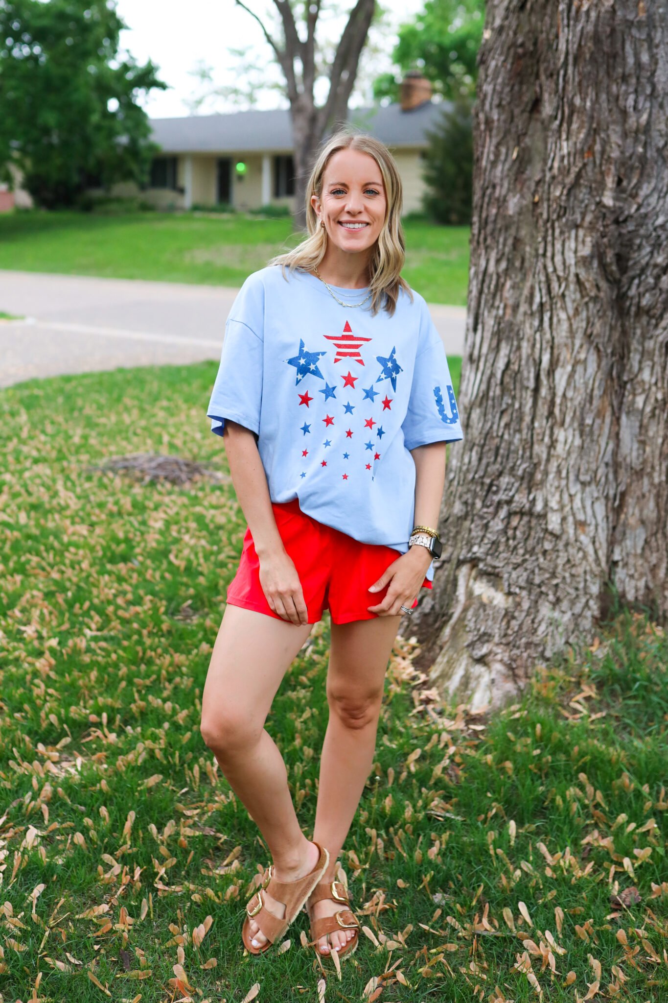 Easy glittery patriotic tee, red shorts, and big-buckle Birkenstocks styled for a laid-back, post-sunset 4th of July evening.