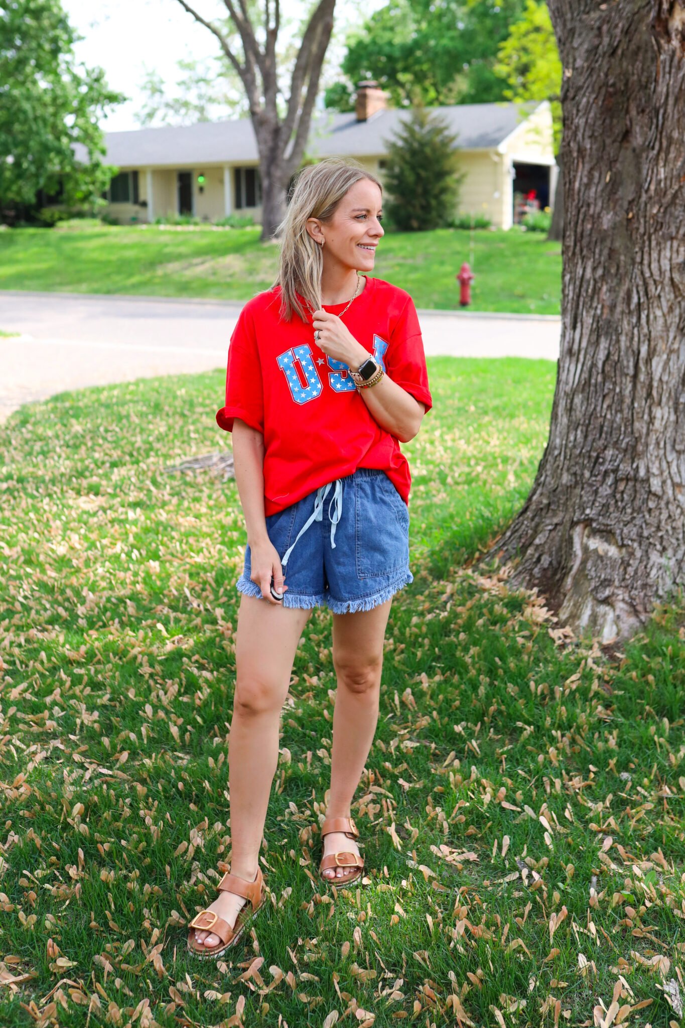Red oversized USA t-shirt paired with drawstring shorts featuring star and stripe back pockets, styled with caramel sandals.