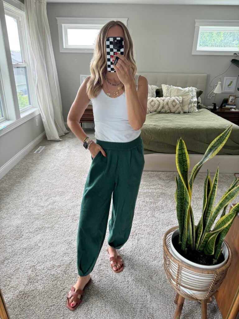 Woman in green knit pants and white tank top.