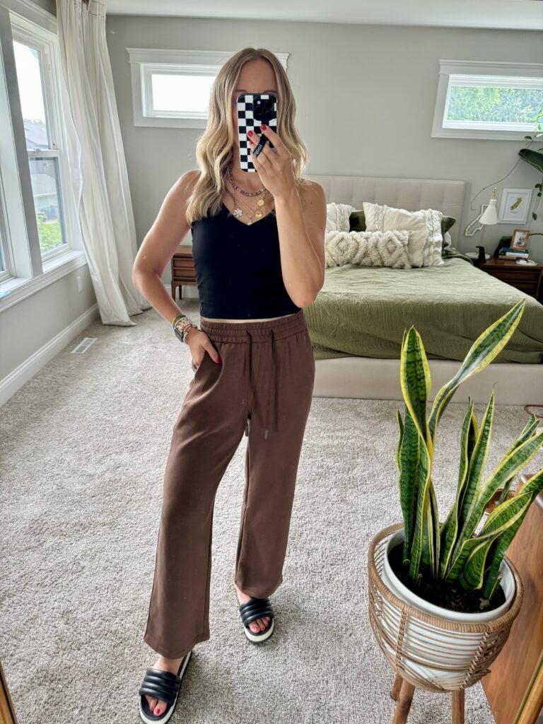 Woman in brown lounge pants and black tank top.