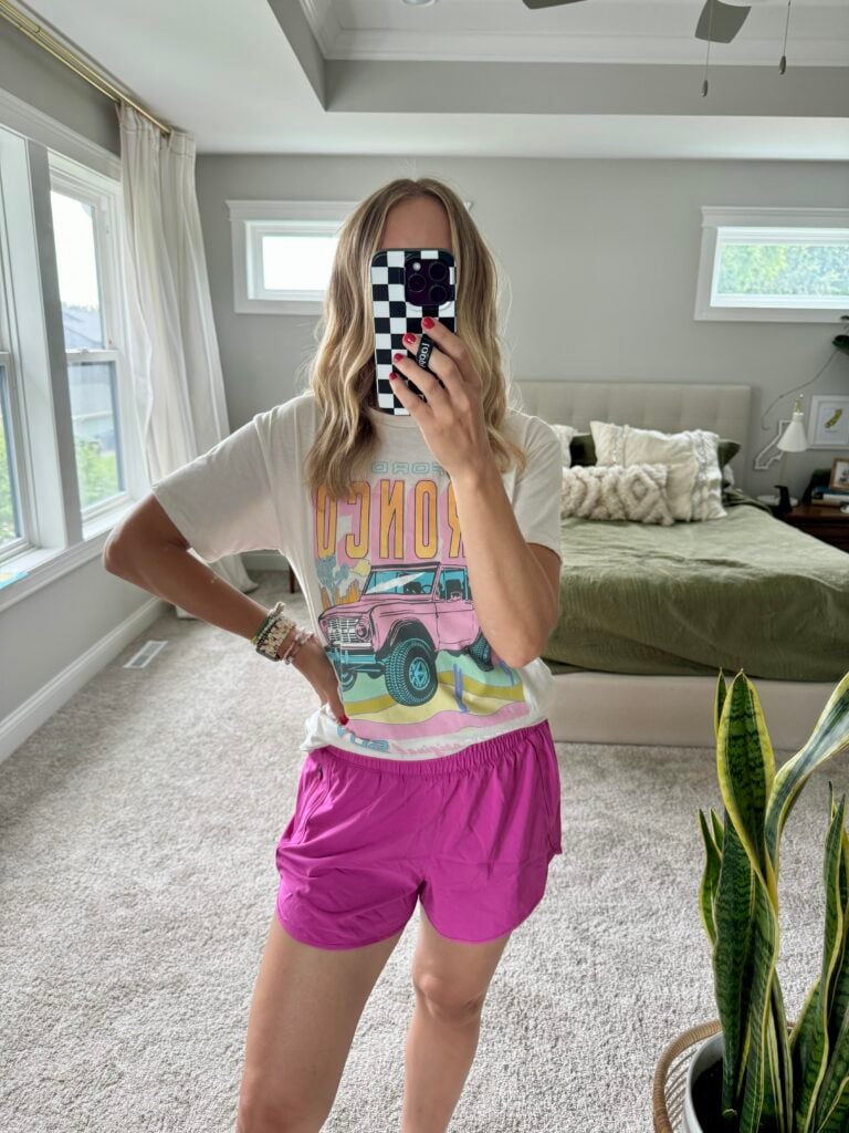 Woman in pink athletic shorts and graphic tee.