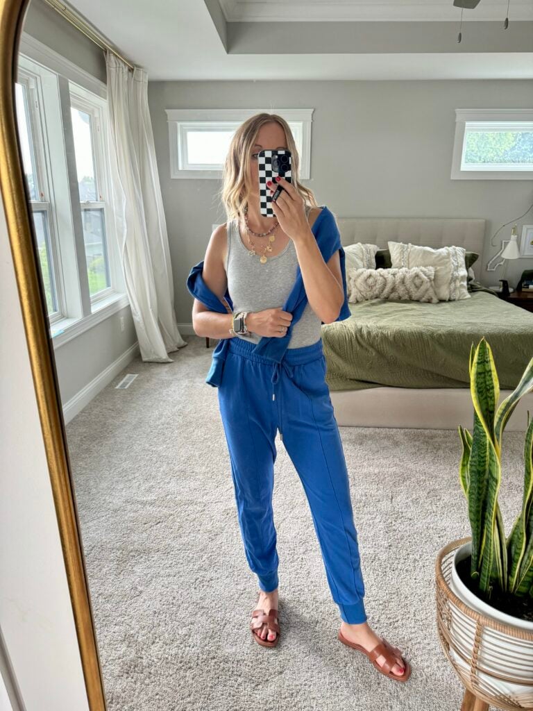 Woman in blue pants, grey tank and matching blue sweatshirt.