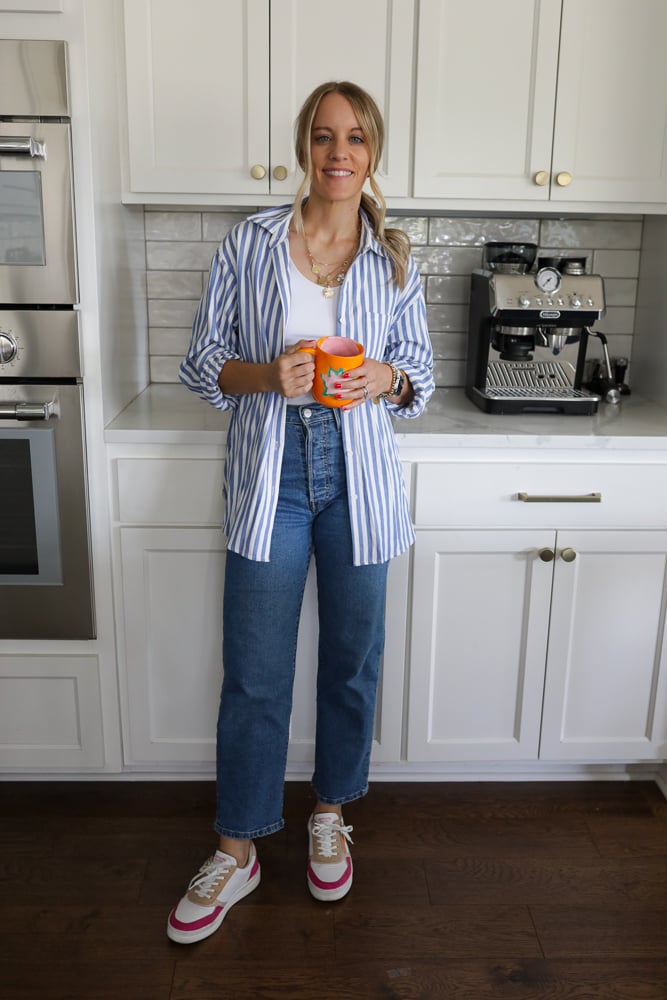 Woman in jeans, a white tank and blue and white stripe button down.