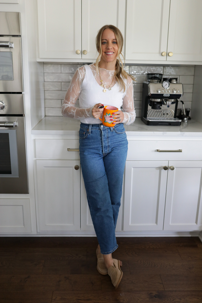 Woman in jeans, a white tank and lace top.