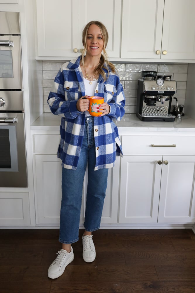 Woman in jeans, a white tank and blue and white checkered shacket.