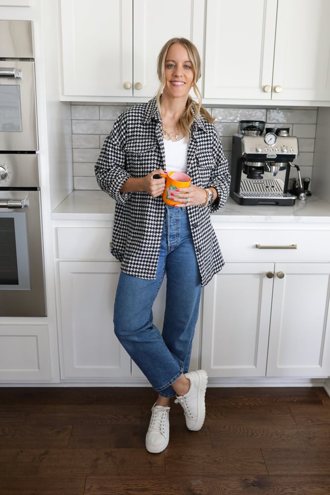 Woman in jeans, a white tank and houndstooth shacket.