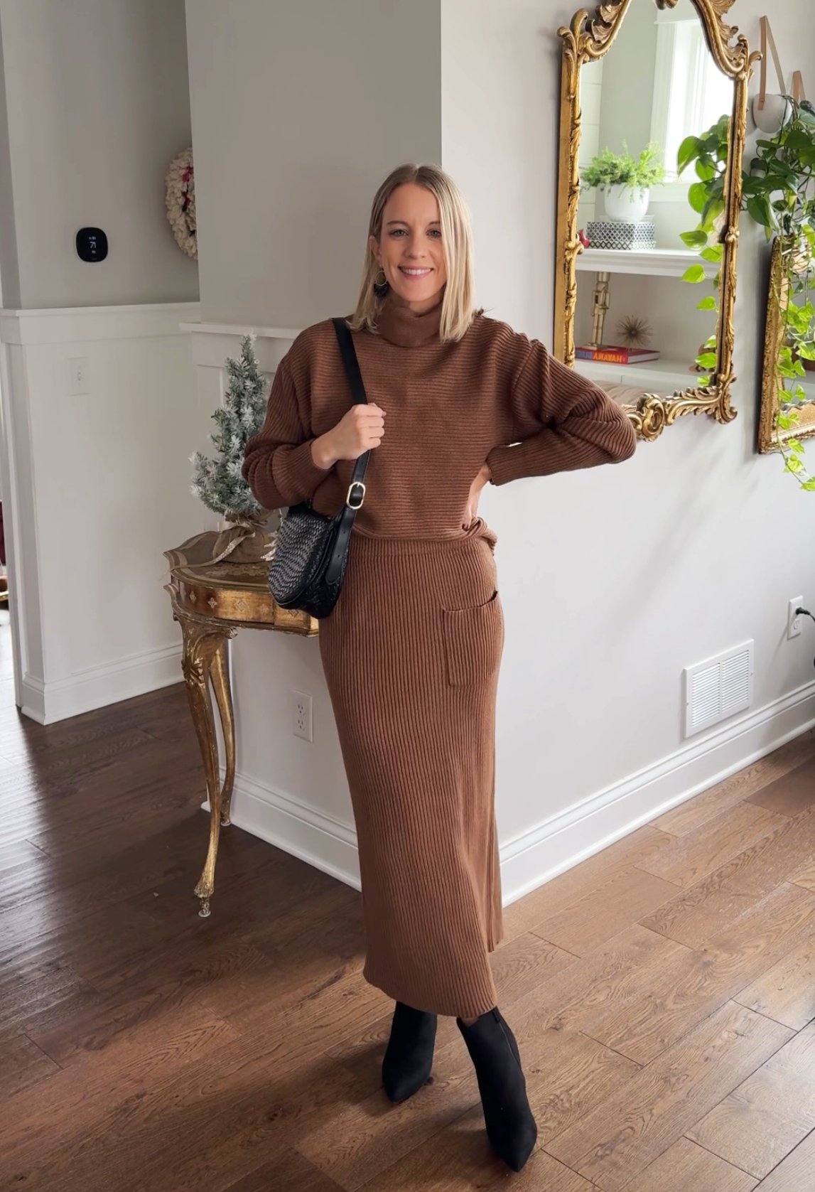 woman wearing a brown sweater and matching skirt, black purse, black boots