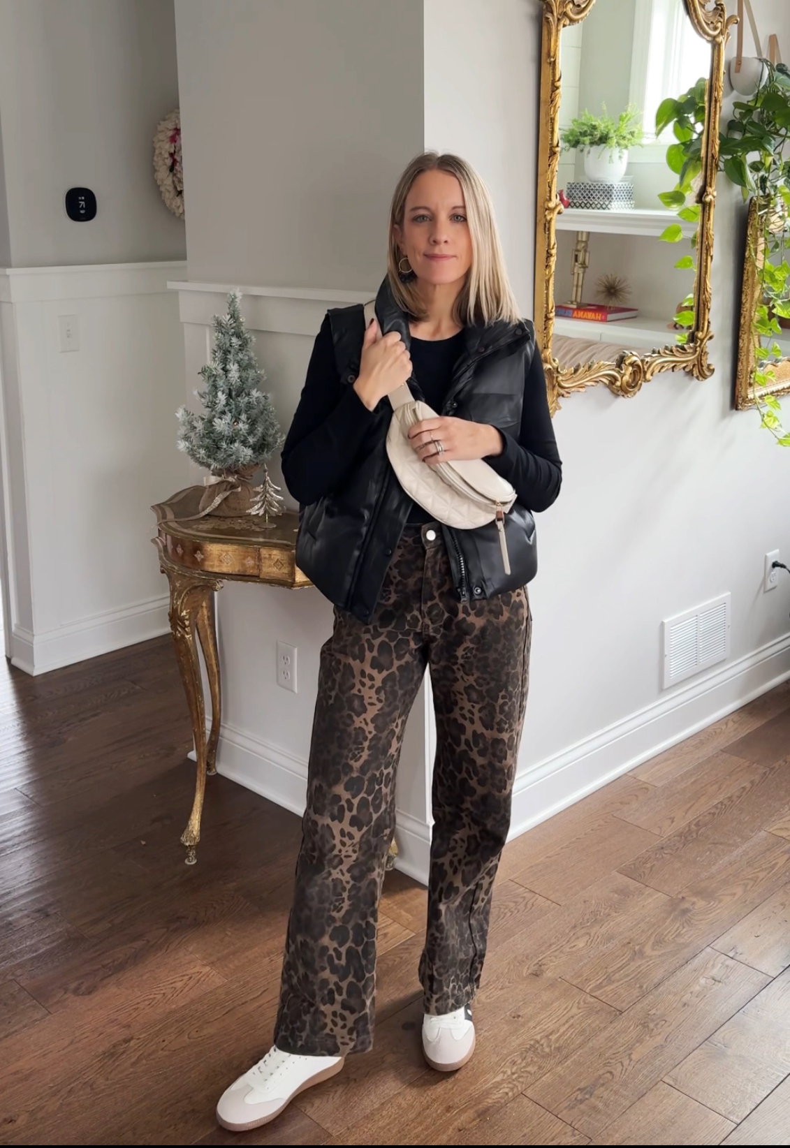 woman wearing a black long sleeve, puffer vest, leopard pants, and sneakers