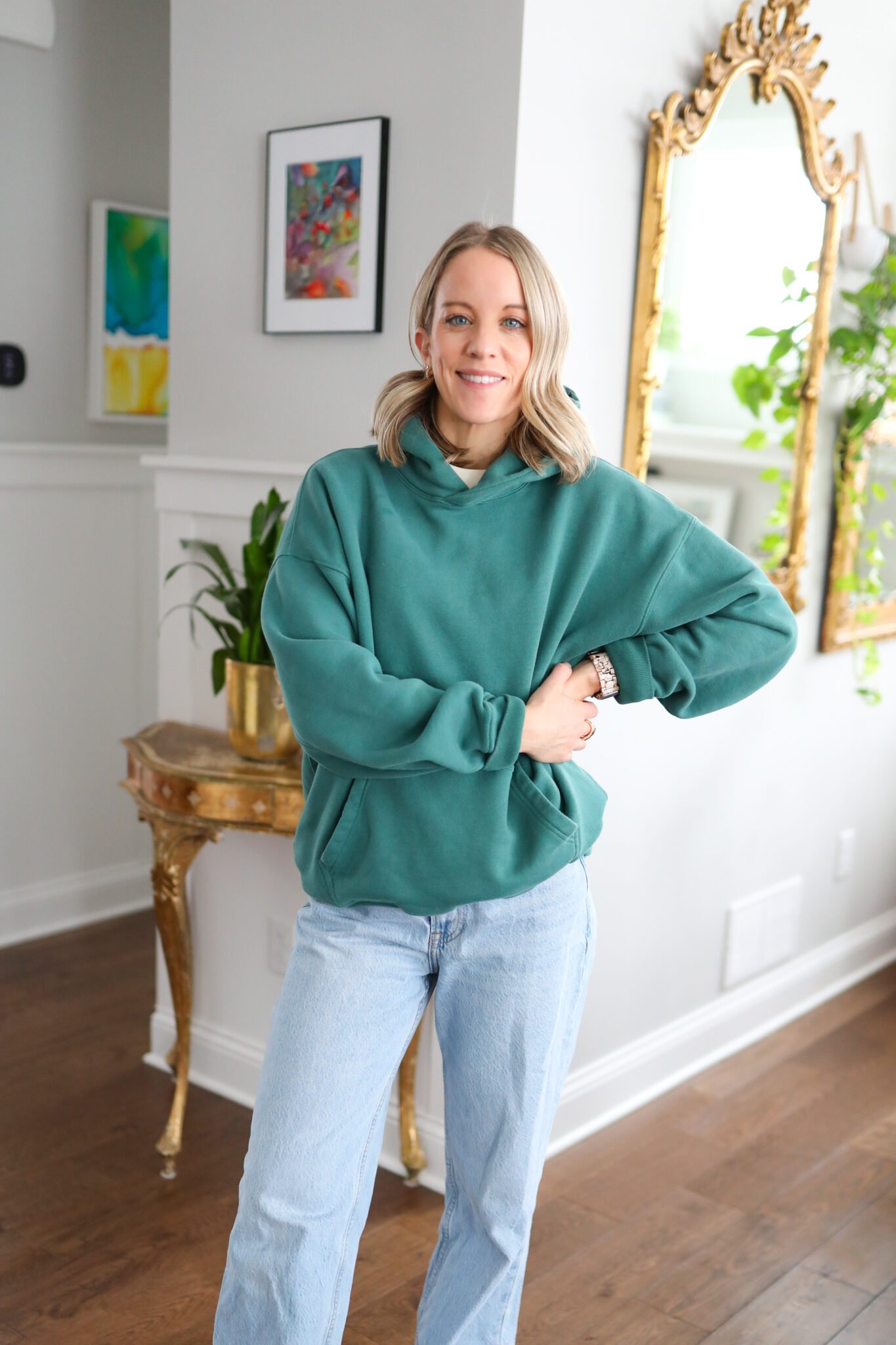 woman wearing green hoodie and wide leg jeans.