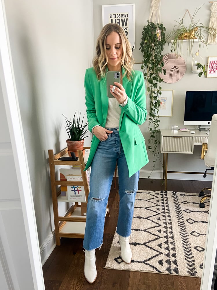 woman wearing a t shirt, green blazer, jeans, and white booties