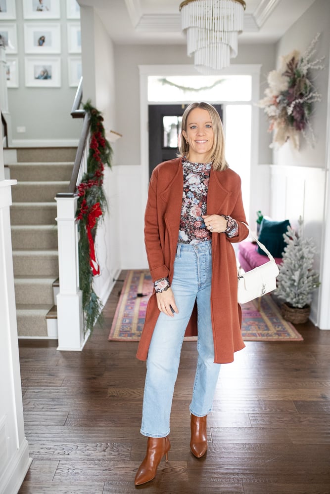 woman wearing floral blouse, denim jeans, leather booties, white purse, and coatigan