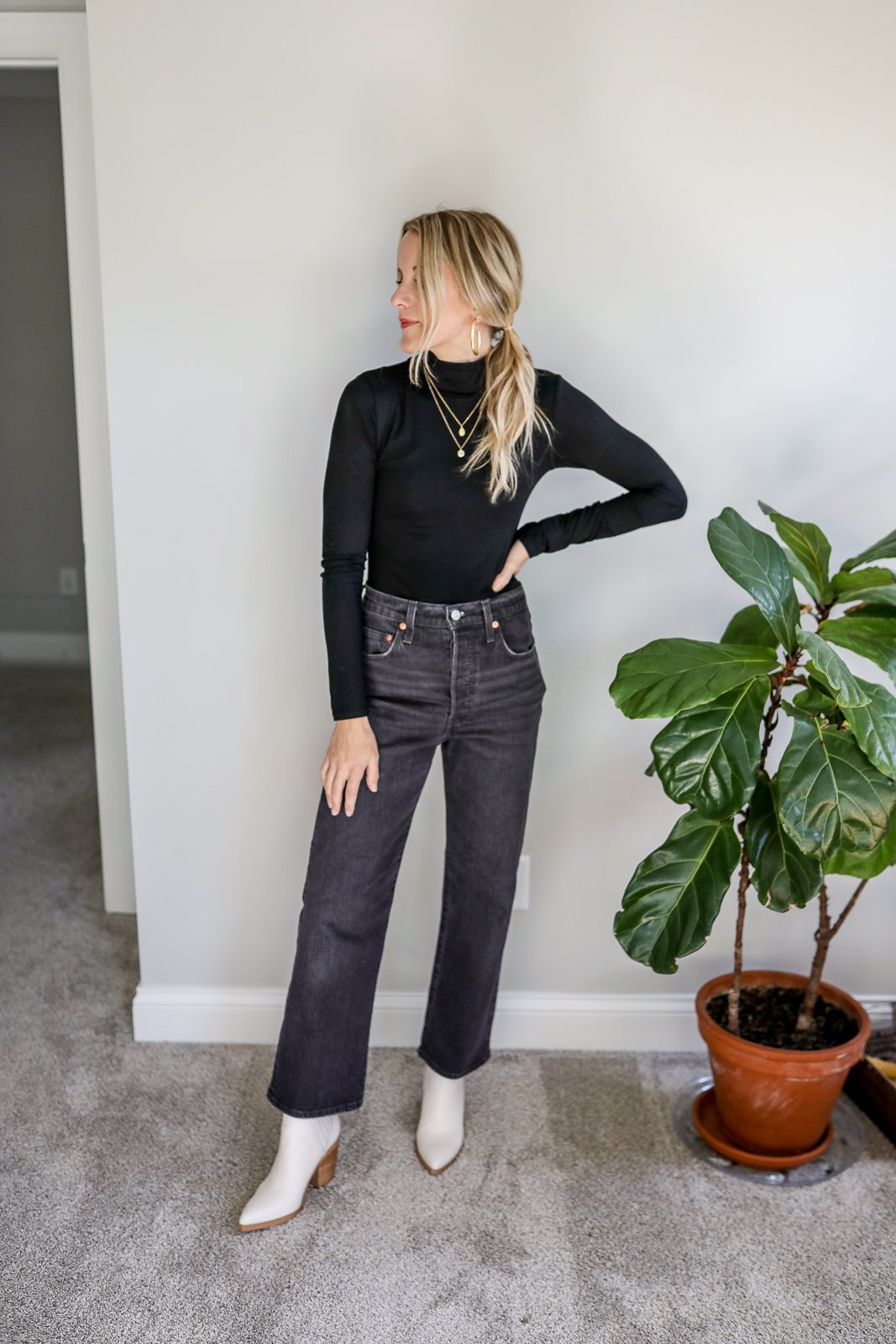 woman wearing a black turtleneck, black jeans, and booties