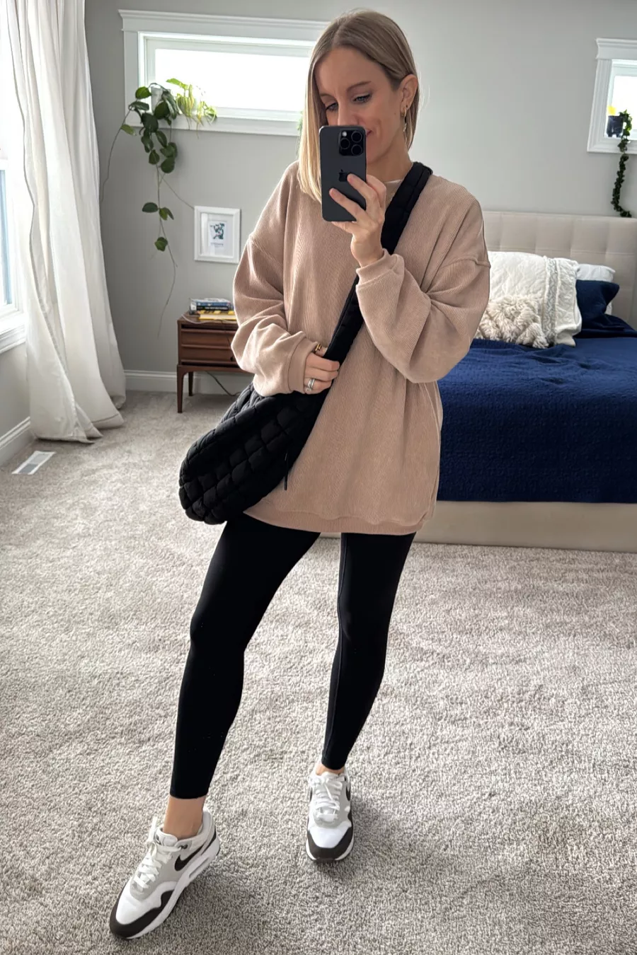 woman wearing corduroy sweatshirt, leggings, and puffer jacket purse.