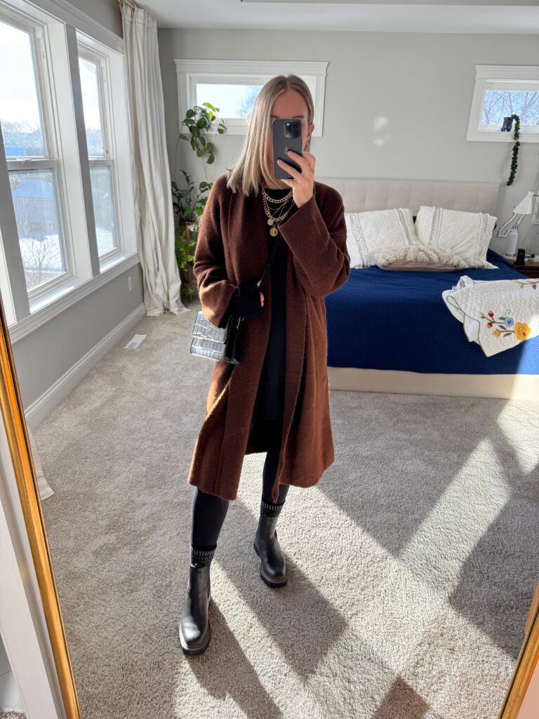 Woman in black pants, black boots and long brown cardigan
