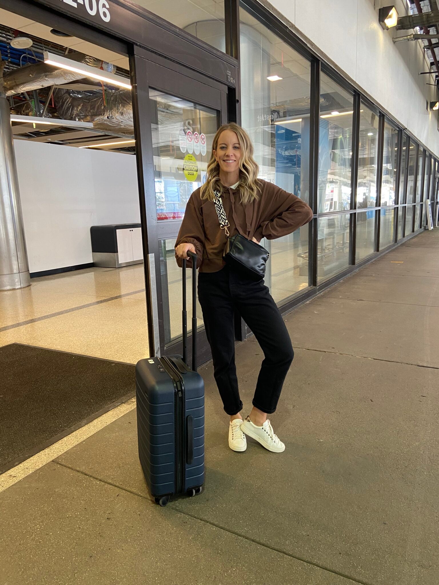 Woman in black pants, brown sweatshirt and sneakers