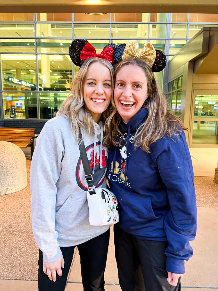 Two women in disney ears and sweatshirts