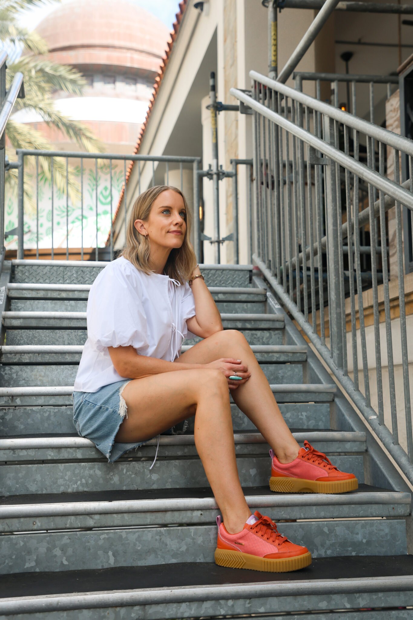 woman wearing white blouse with shorts and red sneakers