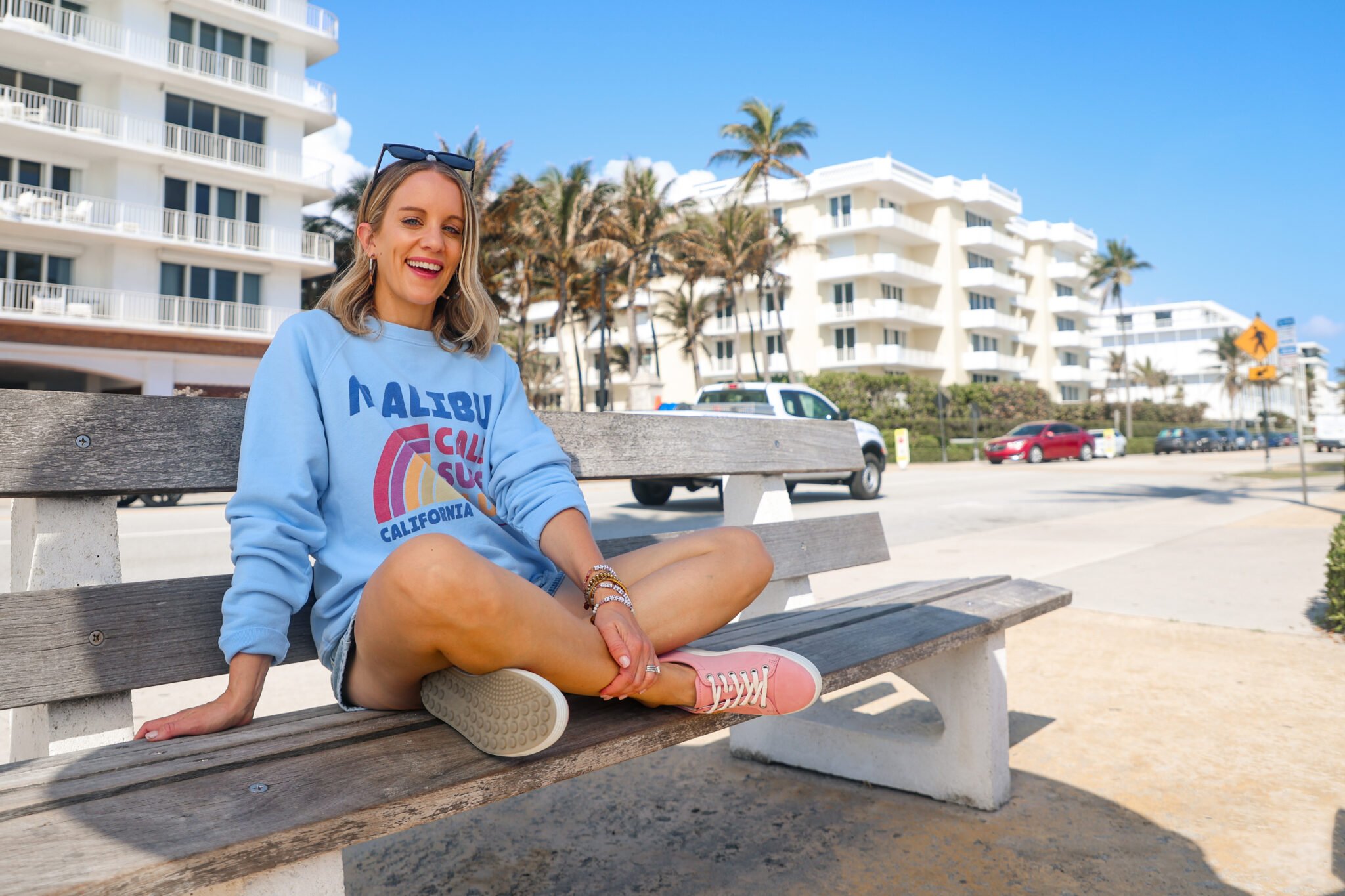 woman wearing blue sweatshirt shorts and pink sneakers