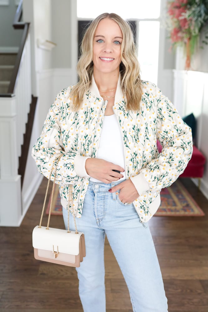 woman wearing floral bomber jacket and blue jeans