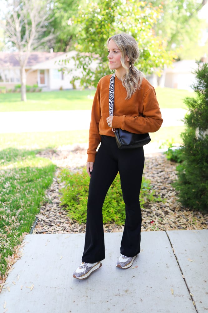 woman wearing orange sweatshirt and black pants