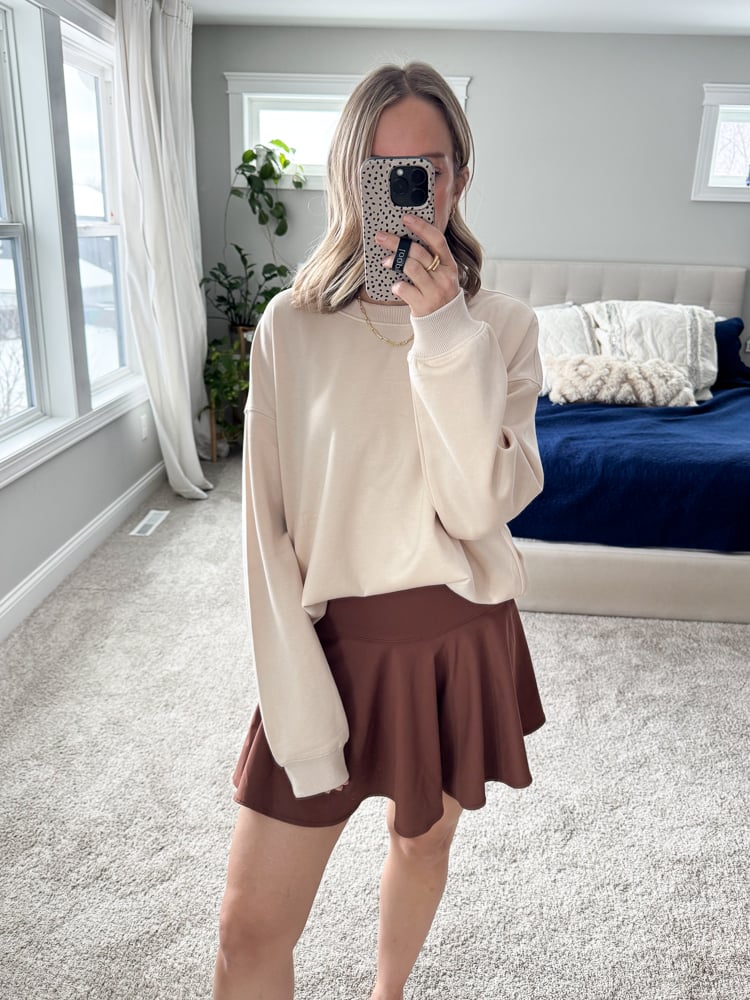 woman wearing beige sweatshirt and brown skirt