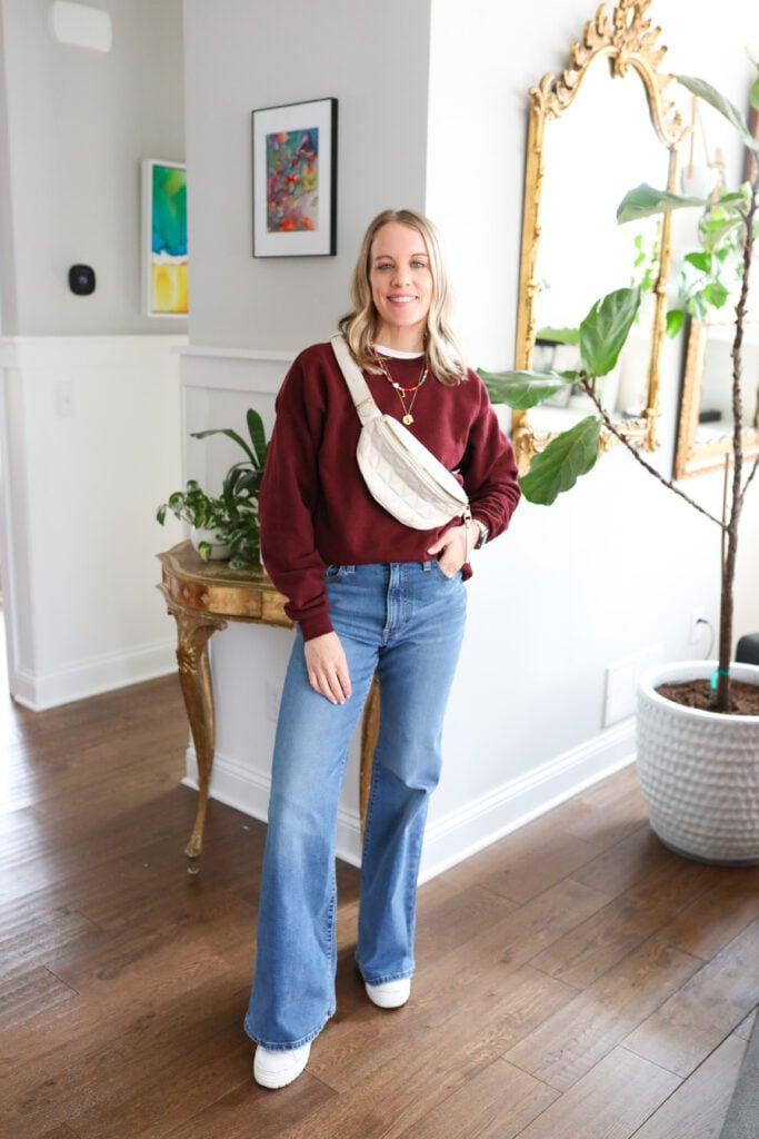 Woman wearing bell bottoms with maroon sweatshirt and sneakers.