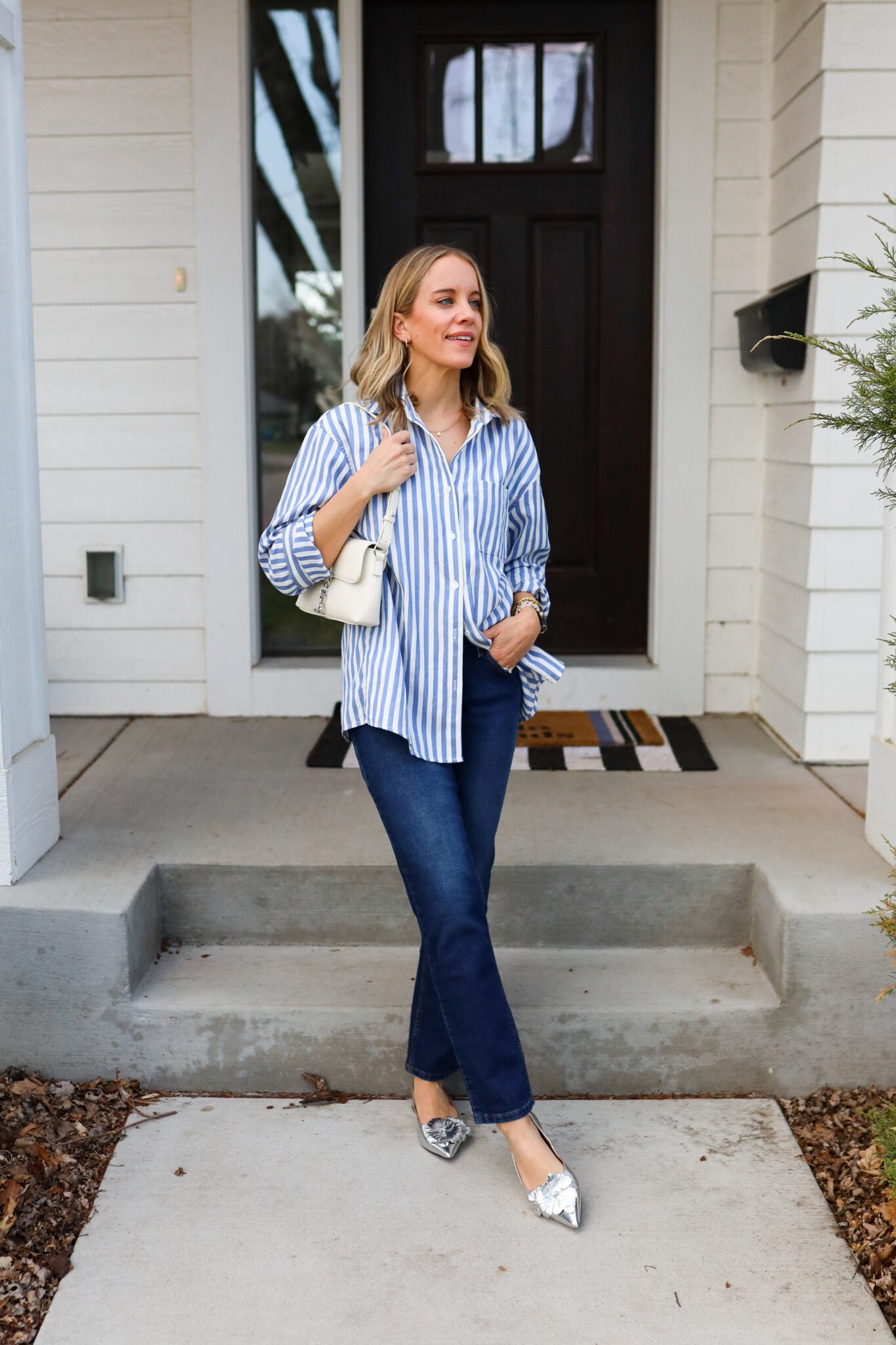 Woman wearing a casual stripped button down with skinny jeans and silver flats