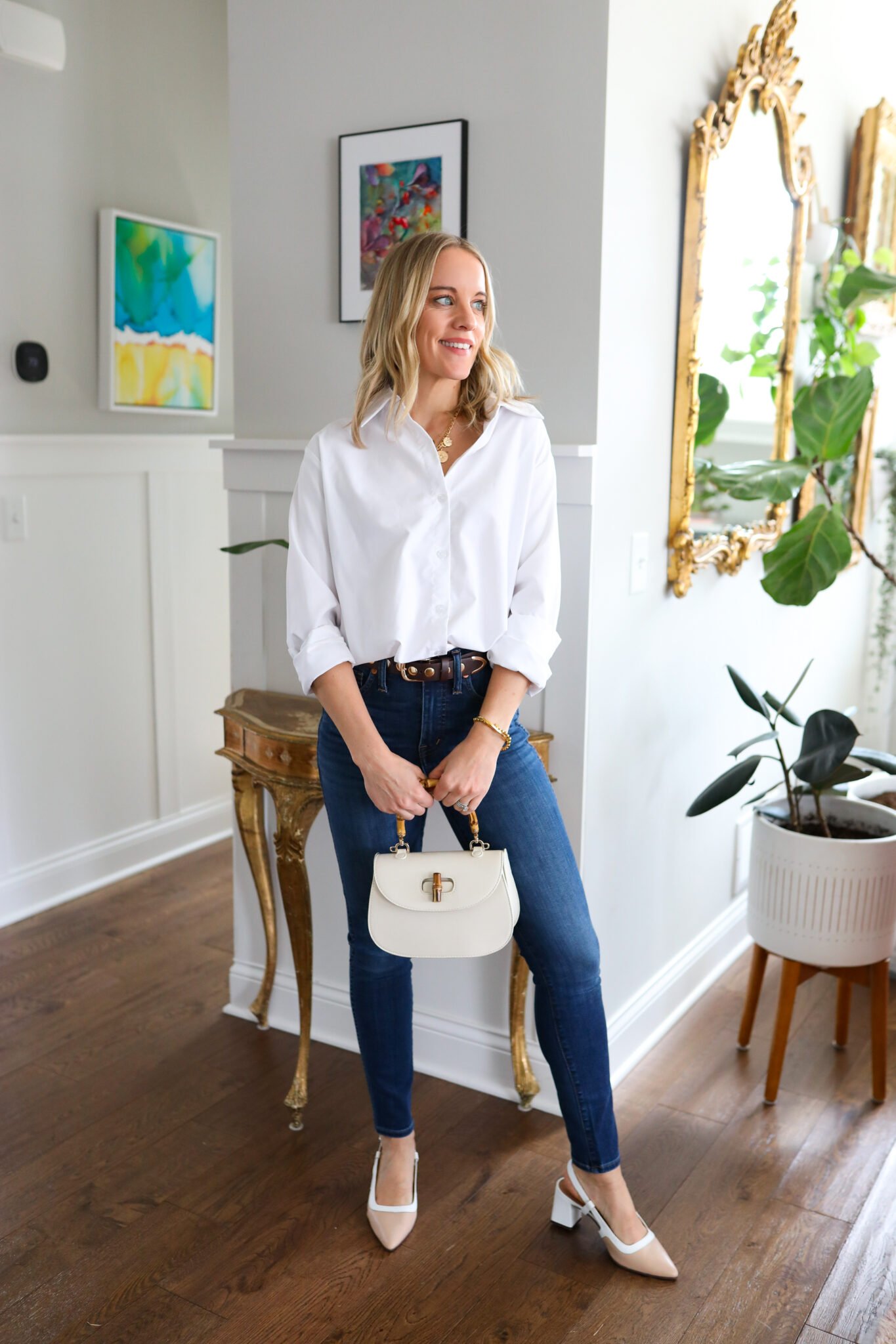 Woman wearing white button down with skinny jeans and neutral kitten heels. Paired with a neutral bag and brown belt