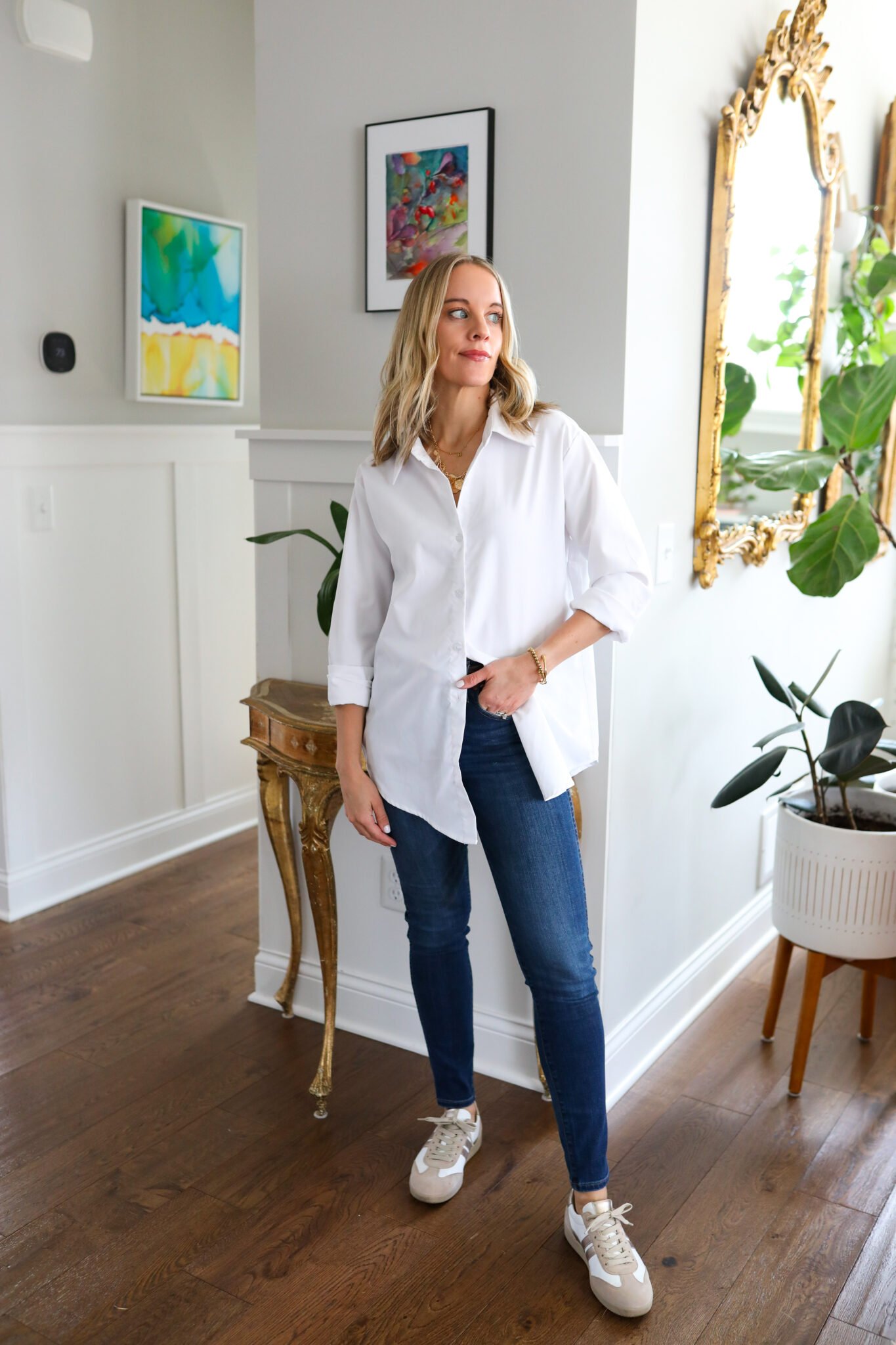 Woman wearing white button down with jeans and sneakers