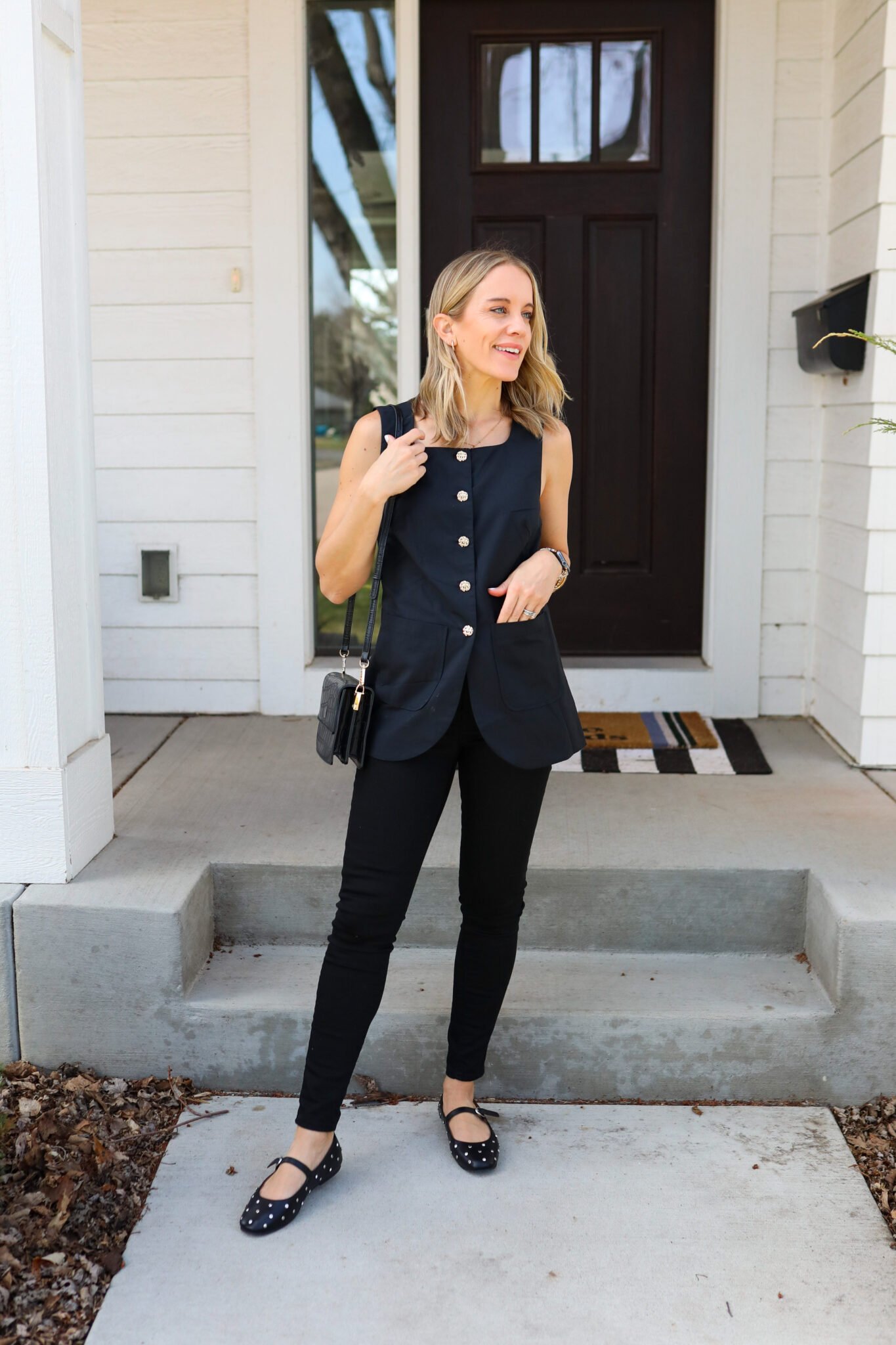 Woman wearing black vest with black skinny jeans and black studded flats 