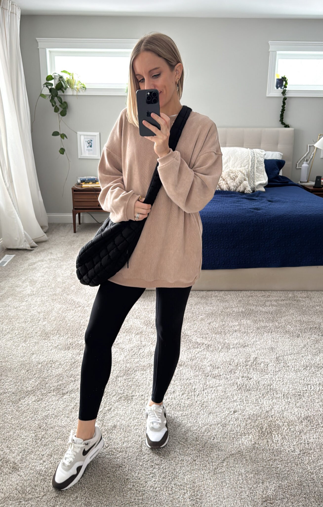 Oversized crewneck sweatshirt, high-waisted no-front-seam leggings with pockets, Nike sneakers, and a puffer belt bag.