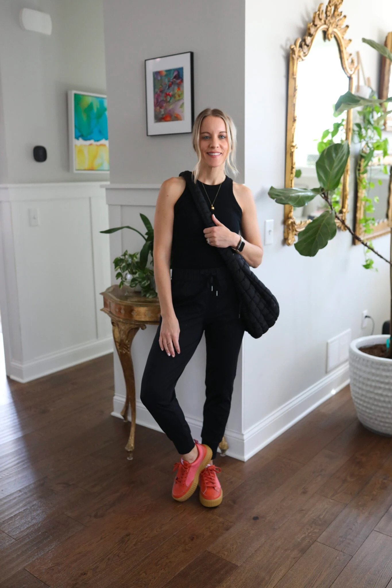 All-black outfit with a ribbed high-neck tank, drawstring joggers, and red Sorel Ona Ave sneakers.