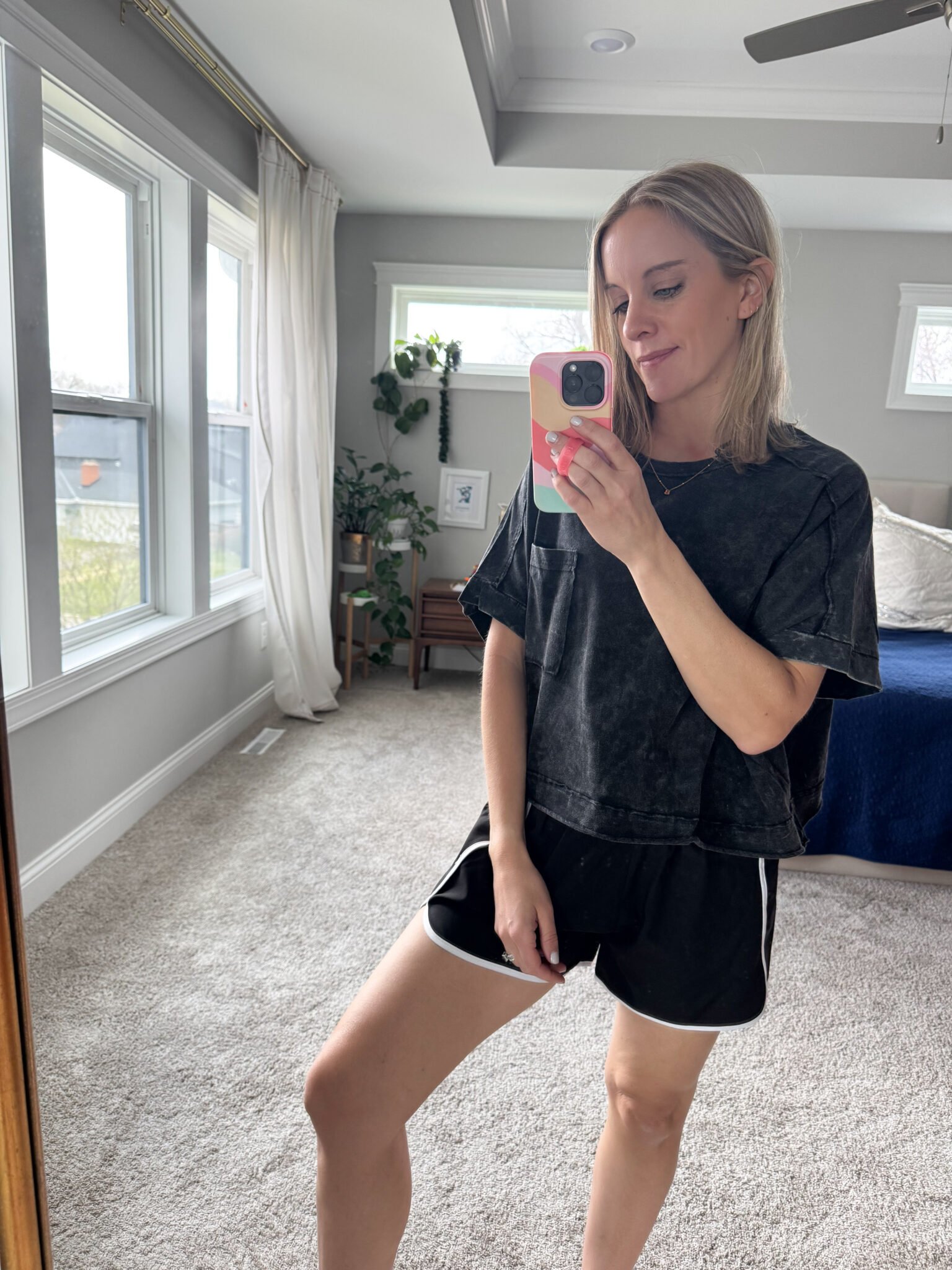 Black slightly cropped oversized washed tee paired with black shorts featuring a white trim, styled with comfy sneakers.