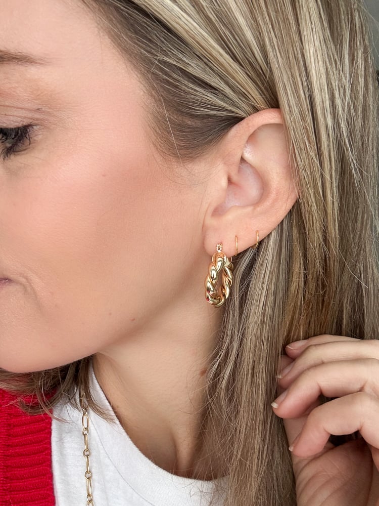 Close-up of ear with two of the three 14K gold-plated hoop earrings from the set in place