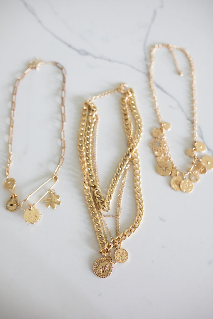 3 Layered charm necklaces on marble counter