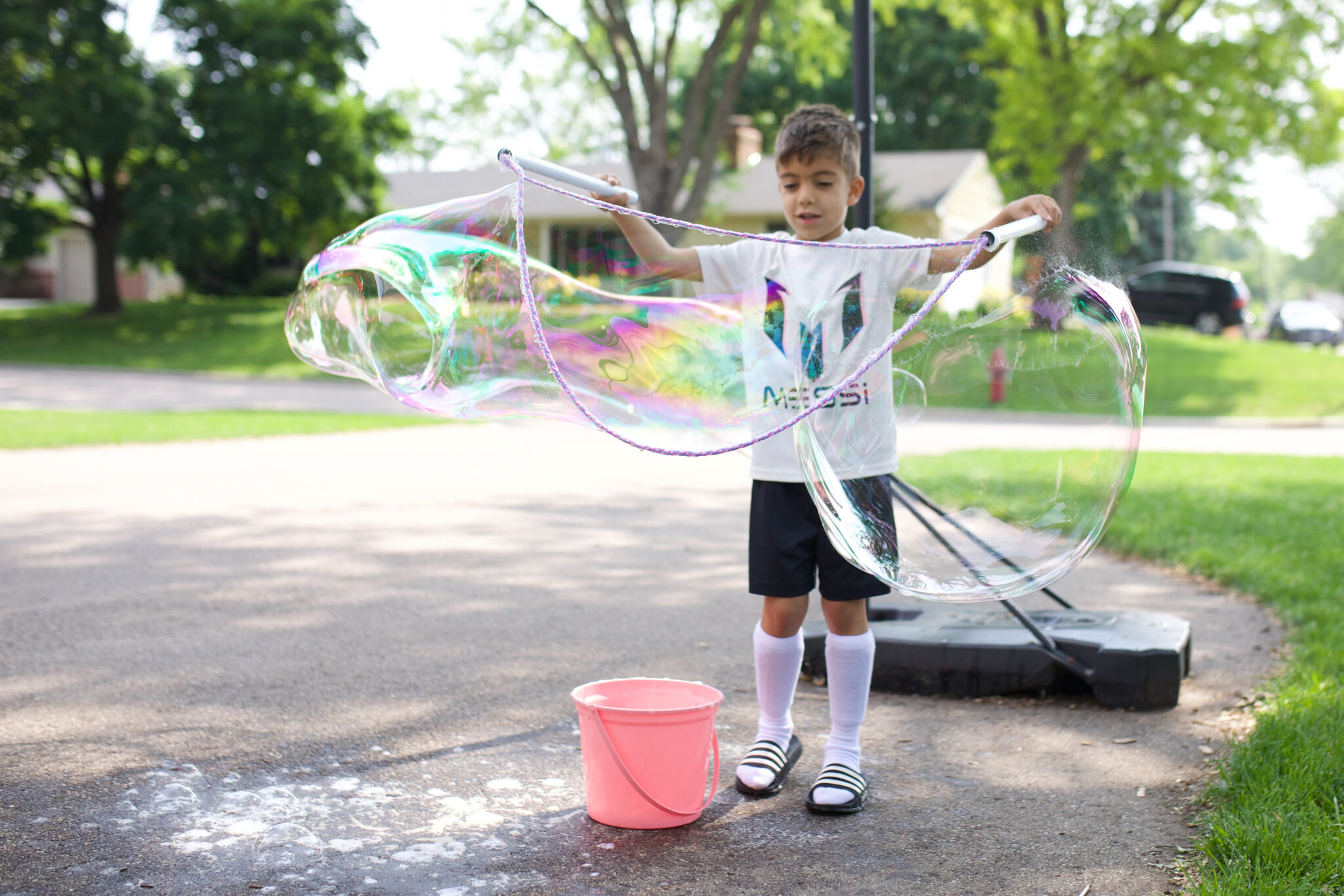 Child creating huge bubbles outside using a unicorn-themed wand from the WOWMAZING bubble kit ( Screen-Free idea )