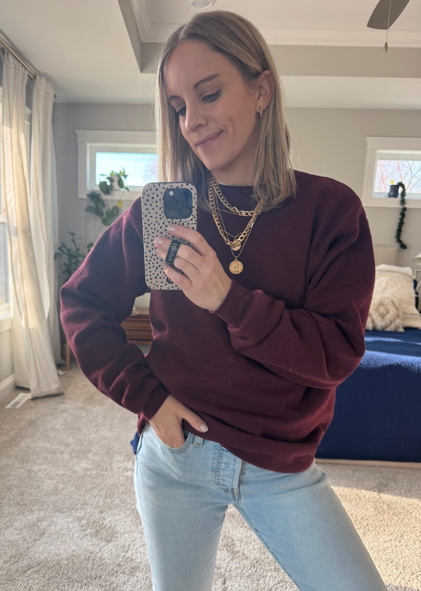 Layered gold coin and chunky chain necklace styled over a simple sweater and jean combo