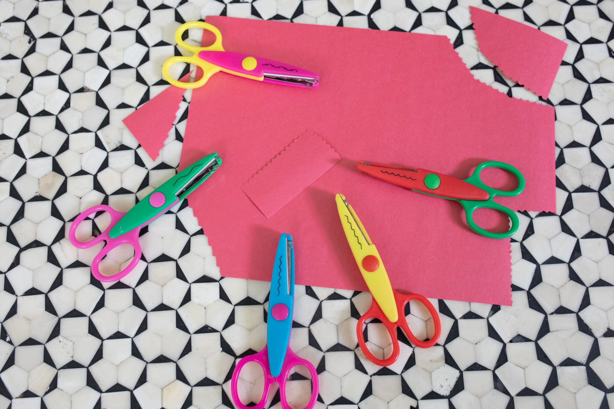 Colorful patterned edge scissors laid out with kid-friendly craft supplies and paper cut into fun shapes. ( Screen-Free idea )